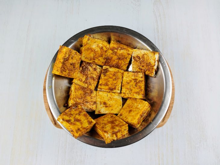 Pedaços de tofu misturados ao mix de temperos.