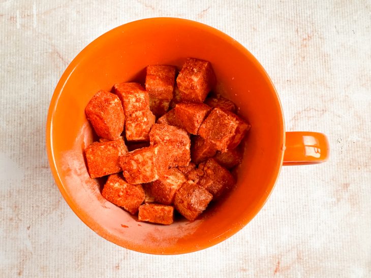 Cubos de tofu empanados na mistura seca descansando por 5 minutos.