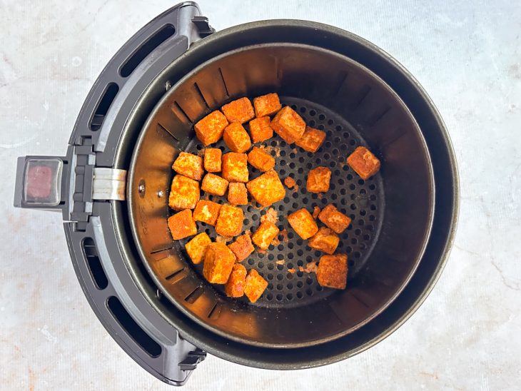 Tofu sendo assado na air fryer a 200 °C até dourar.