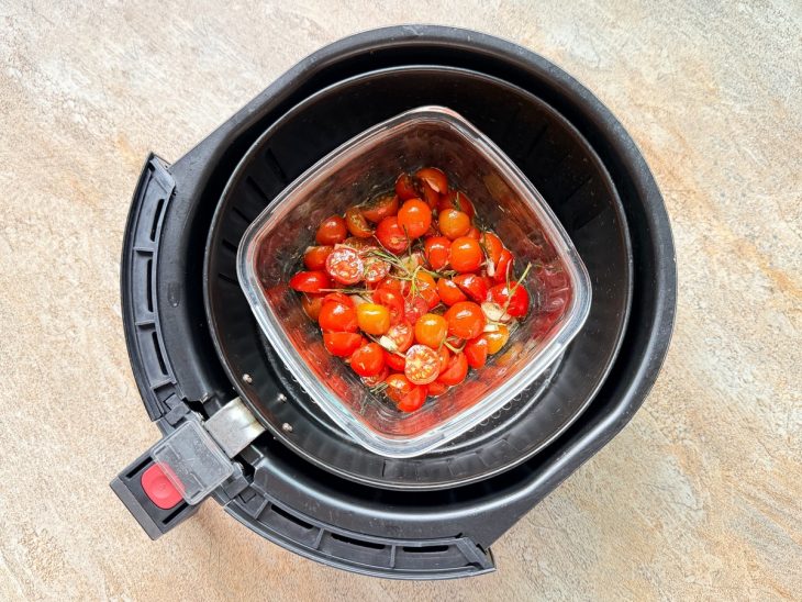 Tomates na airfryer, sendo mexidos durante o cozimento.
