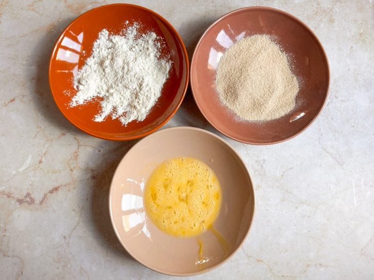 Estação de empanamento com farinha de trigo, ovo batido e farinha de rosca.