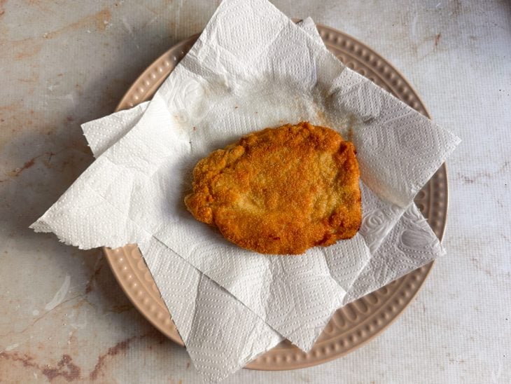 Tonkatsu escorrendo em papel-toalha após a fritura.