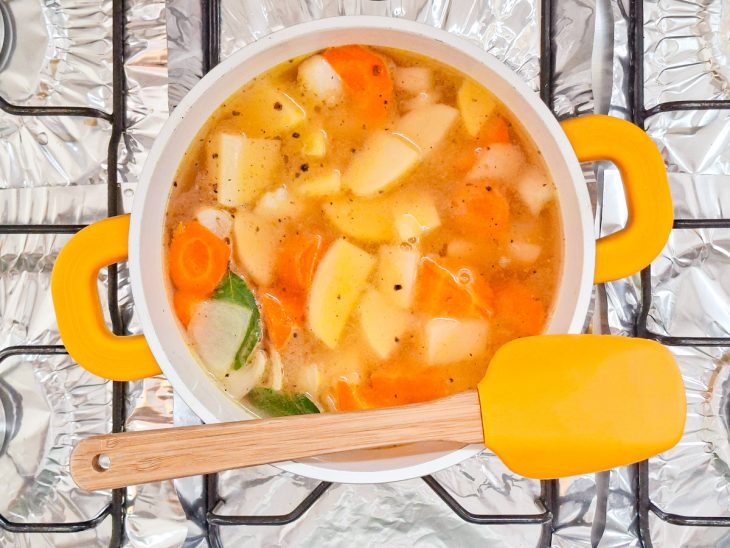 Legumes cozinhando no caldo com folhas de louro.