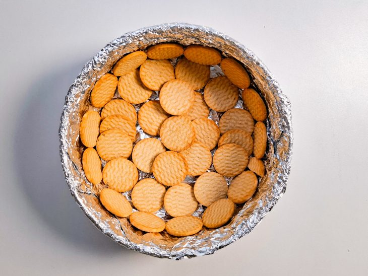 Forma forrada com papel alumínio e uma camada de bolacha.