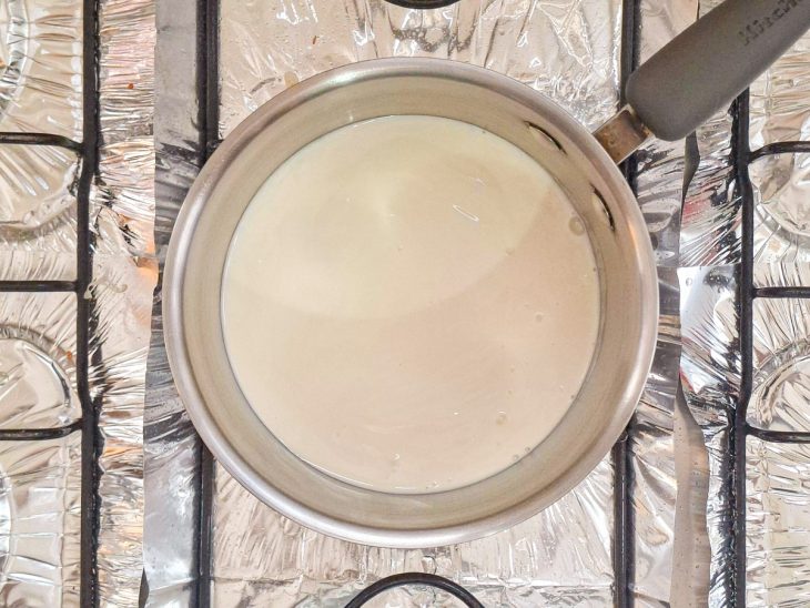 Creme de leite sendo aquecido em panela no fogão sem levantar fervura.