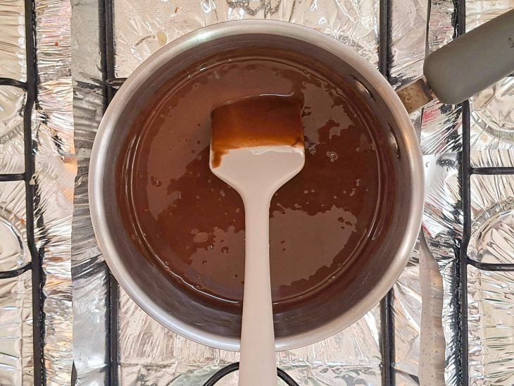 Creme quente sendo despejado sobre o chocolate picado e misturado até formar uma ganache brilhante.