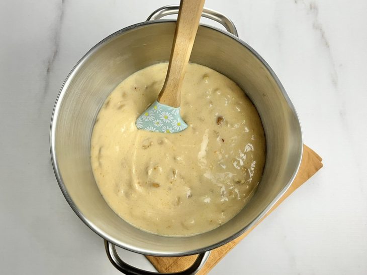 Uma panela com a mistura de açúcar, gemas de ovo, manteiga, creme de leite e amendoins.