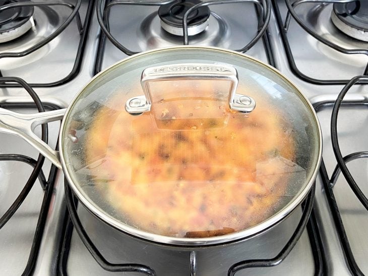 Uma frigideira tampada contendo a mistura de arroz.