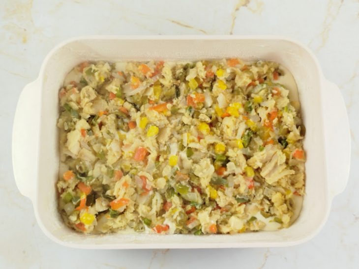 Recheio de bacalhau distribuído sobre a massa de maneira uniforme.