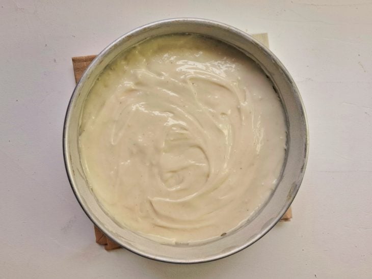 Creme adicionado por cima da camada de bananas na forma.