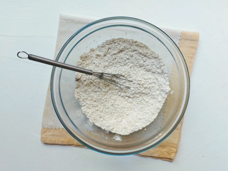 Um recipiente com a mistura de amido de milho, farinha de aveia, farinha de arroz, um pouco de canela, sal, açúcar e fermento.