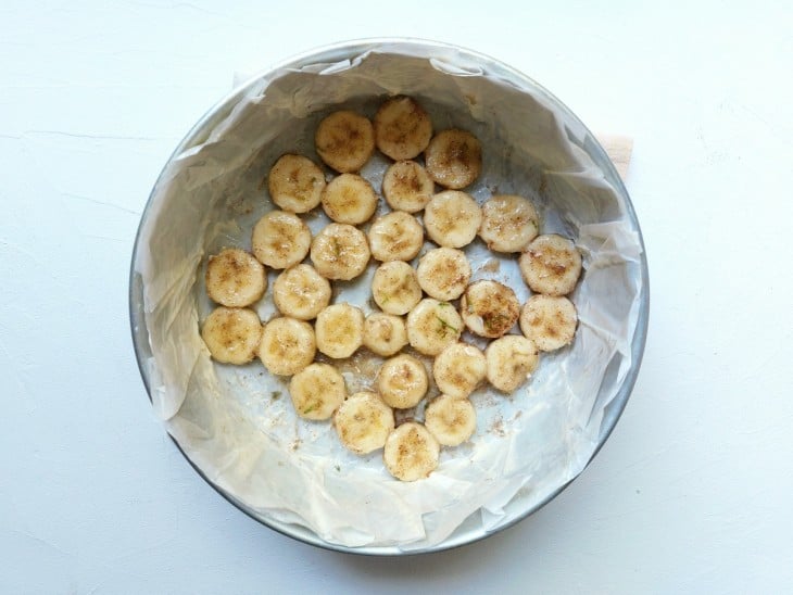 Uma forma redonda forrada com papel mantegia e rodelas de banana.
