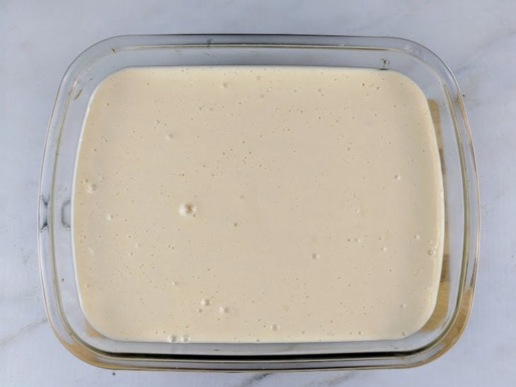 Um refratário com o caramelo, as bananas e a massa da torta.