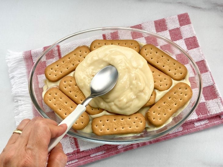 Um refratário com camadas de creme e bolachas maizena.