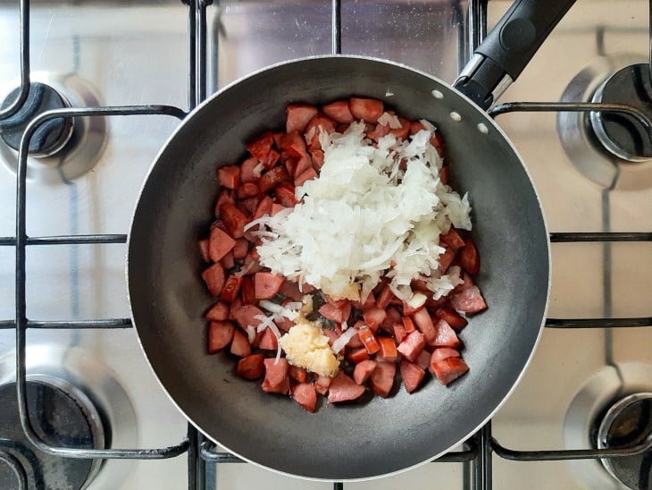 Cebola e alho adicionados a calabresa na frigideira.