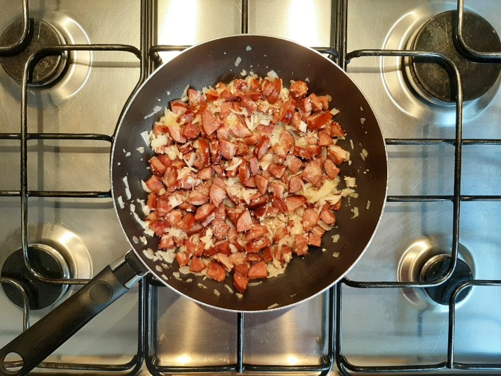 Cebola, alho e calabresa misturados em uma frigideira.