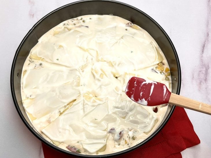 Camada de queijo e requeijão por cima do recheio e massa da torta na forma.