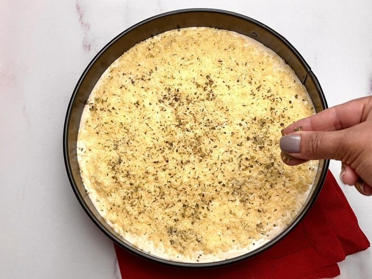 Torta na forma finalizada com o restante da massa e ervas desidratadas e parmesão por cima.