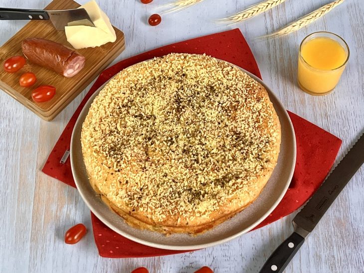 Torta de calabresa cremosa inteira, desenformada, e disposta em um recipiente redondo.