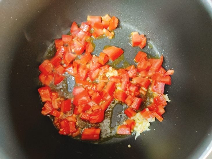 Uma panela com azeite, tomate e alho.