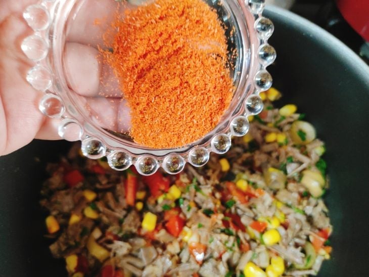 Caldo em pó de carne sendo adicionado ao recheio.