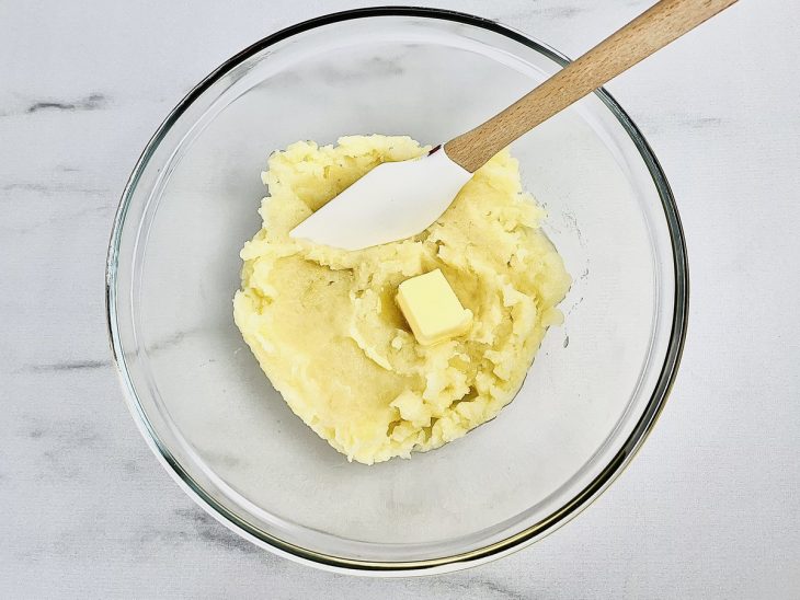 Numa tigela, o purê de batatas liso, com a manteiga.