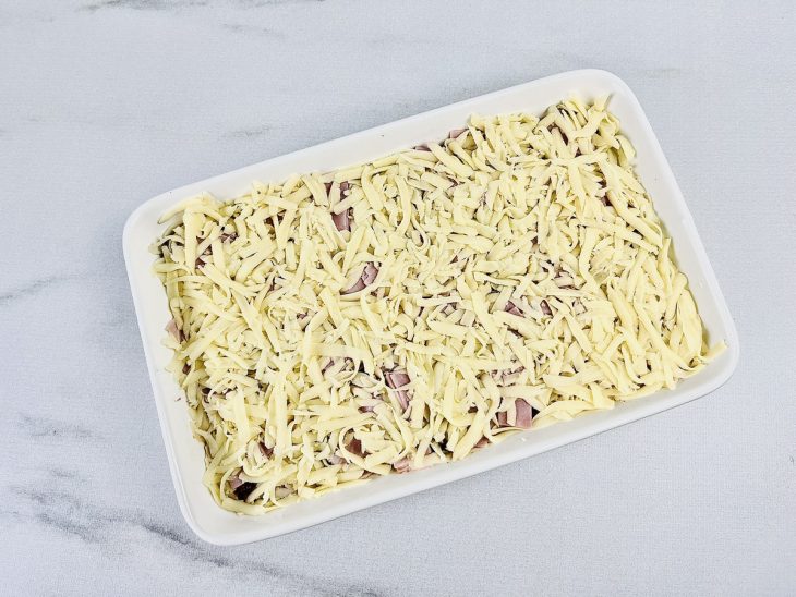 Na travessa, por cima do purê o refogado de carne, o presunto e o queijo mussarela.
