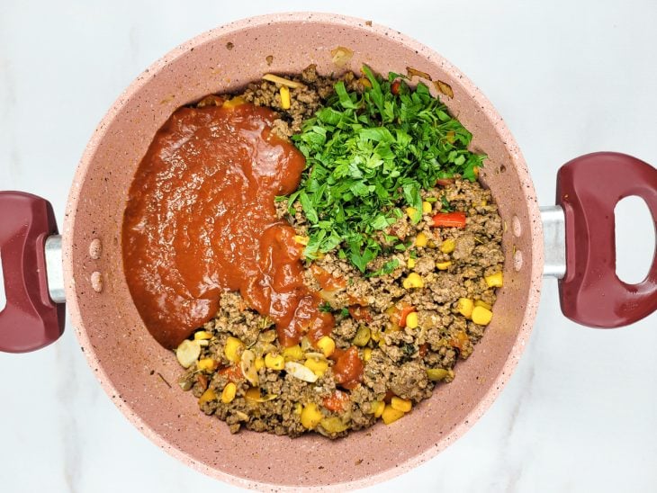 Uma panela refogando carne moída e legumes com molho de tomate.