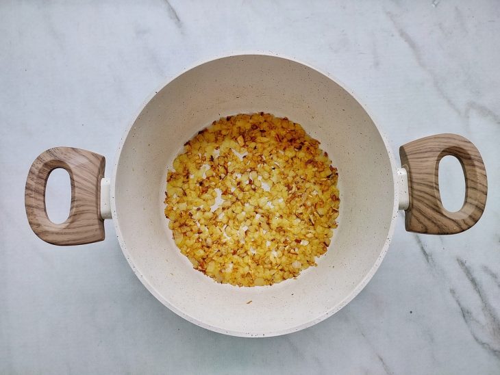 Cebola e alho dourando sobre a panela.