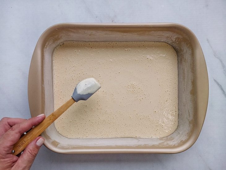Assadeira retangular 20x30 cm untada com metade da massa espalhada.