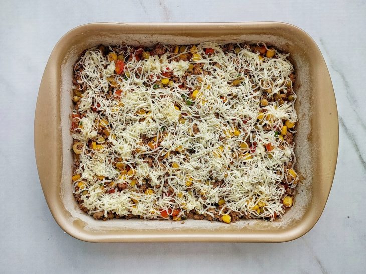 Camada de mussarela sendo adicionada sobre o recheio.