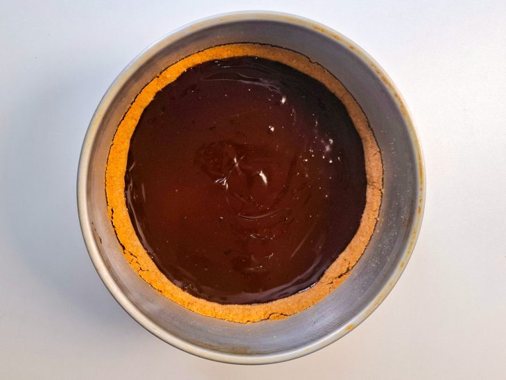 Ganache adicionada sobre a camada de caramelo na forma.