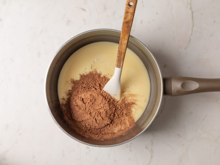 Leite condensado e chocolate em pó numa panela.