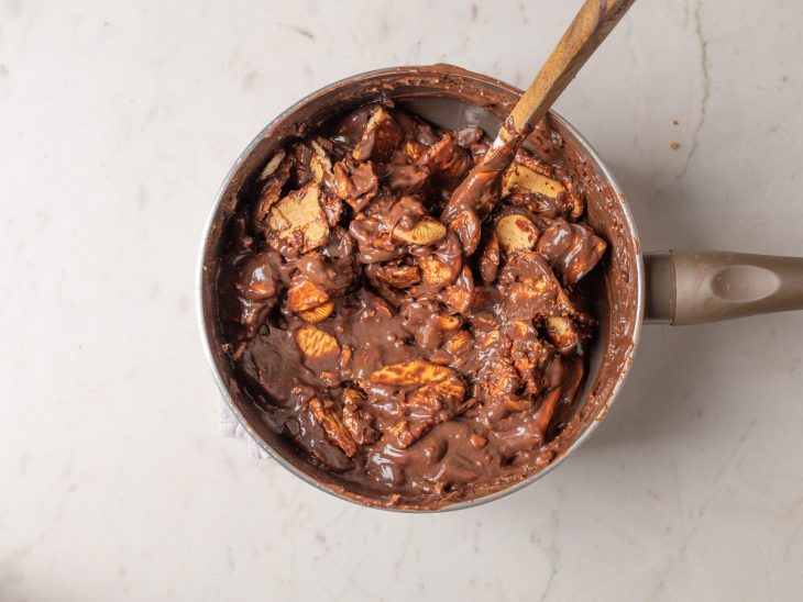 Biscoitos quebrados envolvidos no brigadeiro preparado na panela.