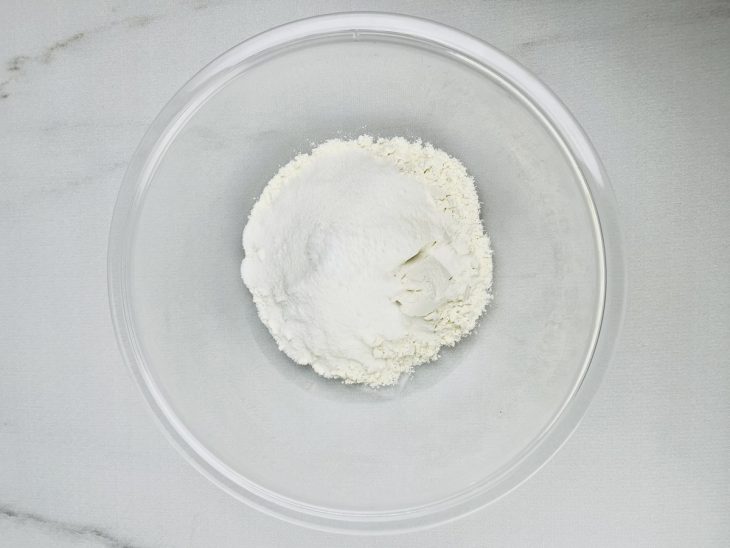 Açúcar, farinha e pitada de sal misturados em uma tigela de vidro.