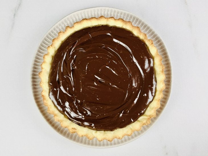 Ganache espalhada sobre a massa da torta.