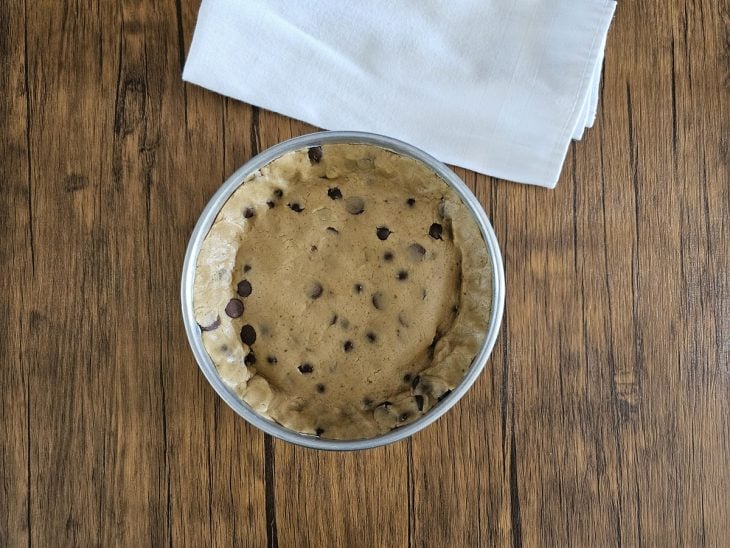 Uma forma forrada com a massa de cookie, recheada com Nutella e coberta com massa.