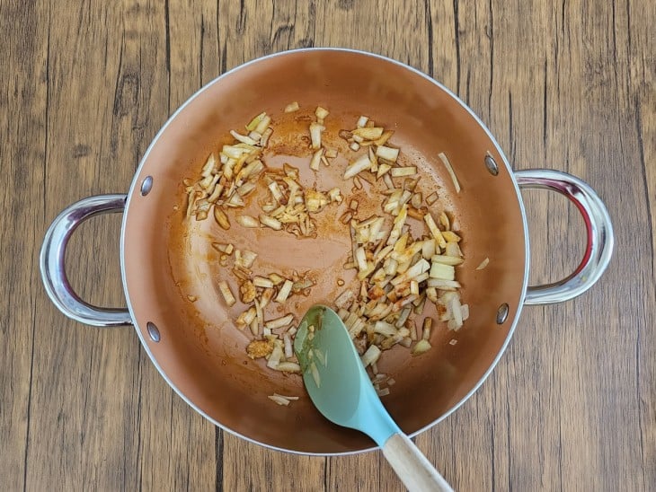 Azeite, cebola, alho e colorau em uma panela.