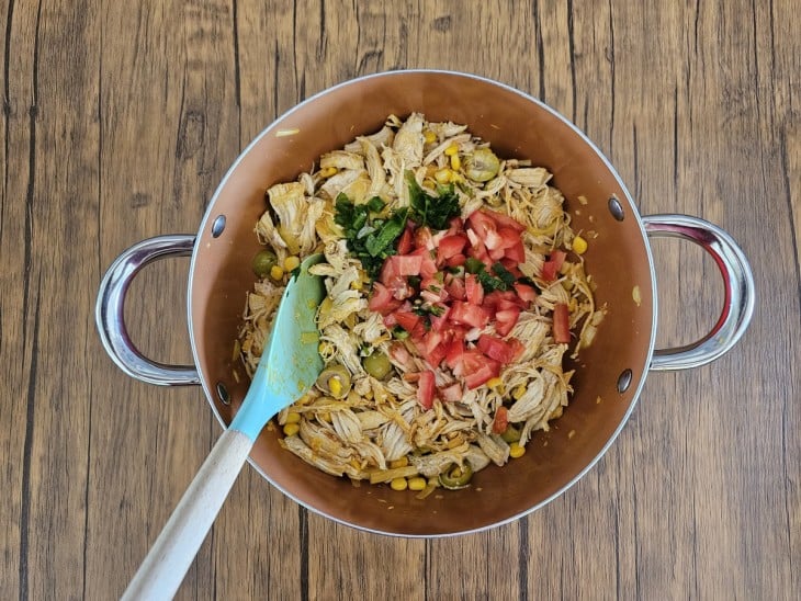 Cheiro-verde e tomate por cima do recheio de frango.