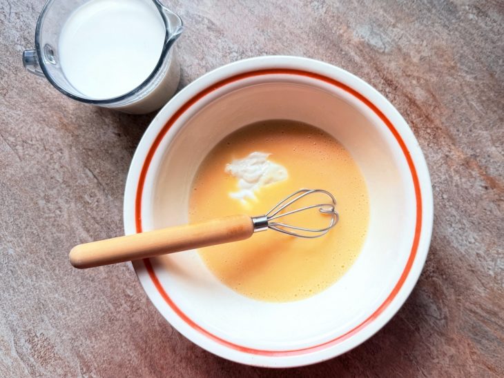 Leite e requeijão sendo adicionados a mistura na tigela.