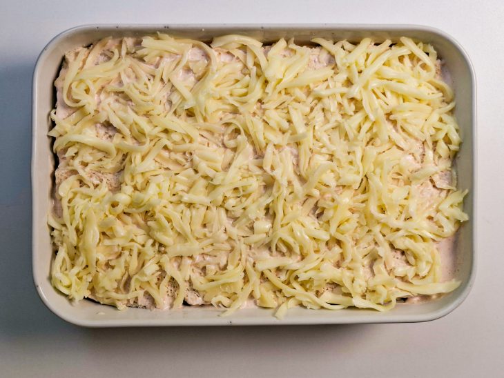 Camadas de queijo e recheio montadas até preencher o refratário.