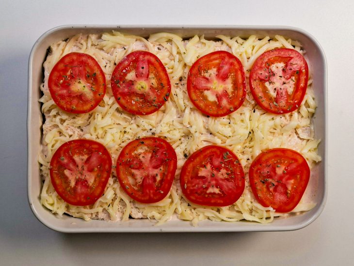 Superfície final com queijo, tomate em rodelas e orégano antes de assar.