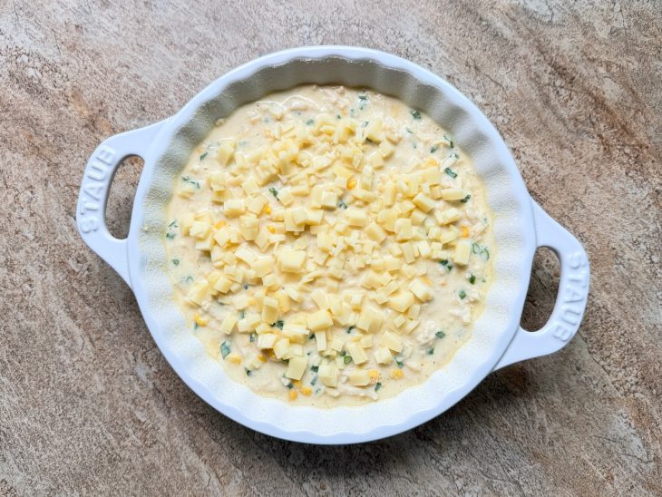 Queijo ralado sendo distribuído por cima da massa.