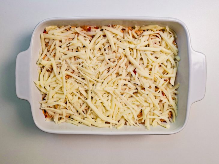 Frango e mussarela ralada adicionada no refratário.