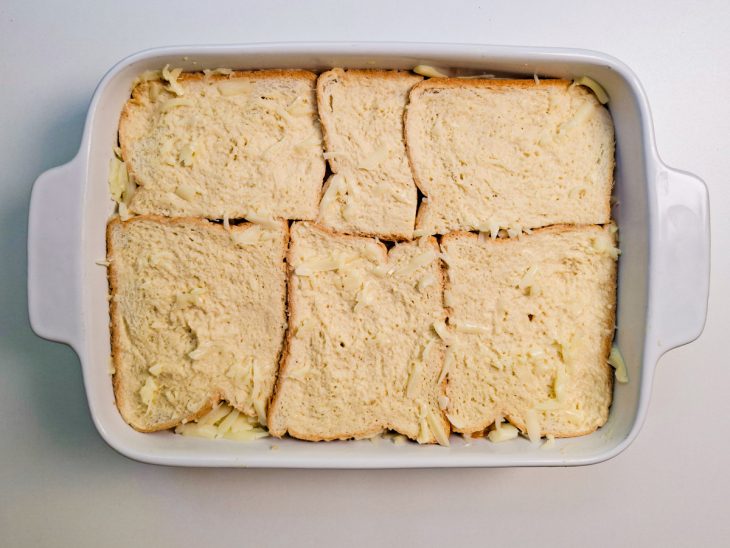 Camada de pão acomodada e mistura despejada no refratário.