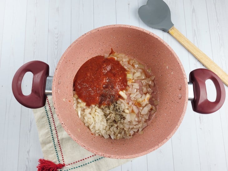 panela com cebola refogada e molho de tomate.