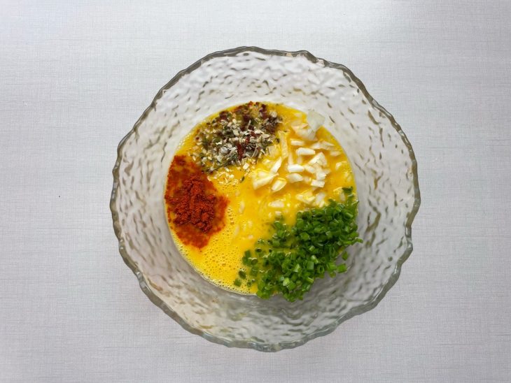 Temperos e cheiro-verde sendo incorporados aos ovos.