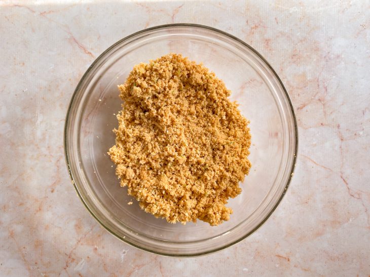 Um recipiente com a farofinha da base da torta.