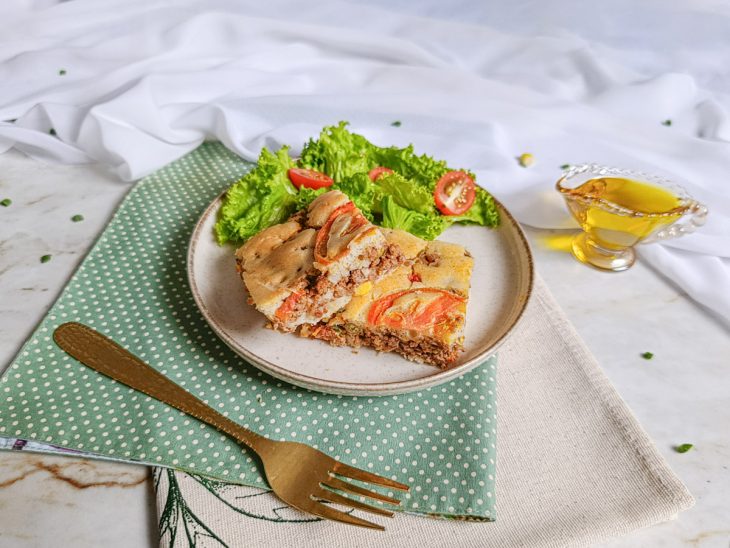 Torta de carne moída assada, dourada e com recheio aparente.