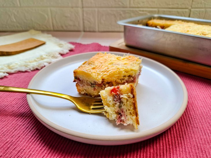 Fatia da torta servida em prato, garfo tirando um pedaço.